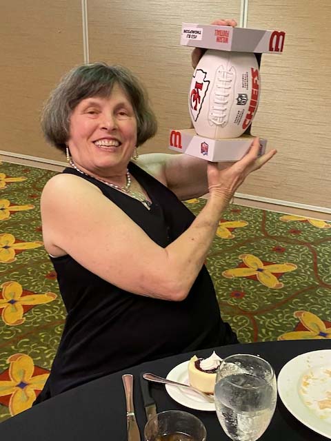 Raffle winner, Marilyn, holding up a signed KC Chiefs football.